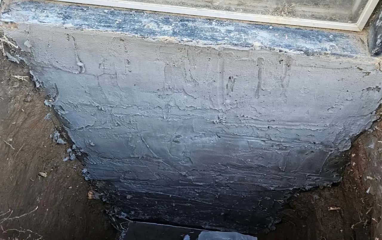 Foundation wall coated with exterior waterproofing