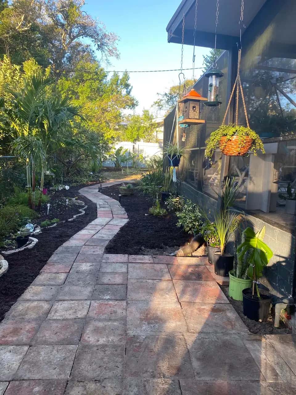 Winding paver path through garden beds with potted plants