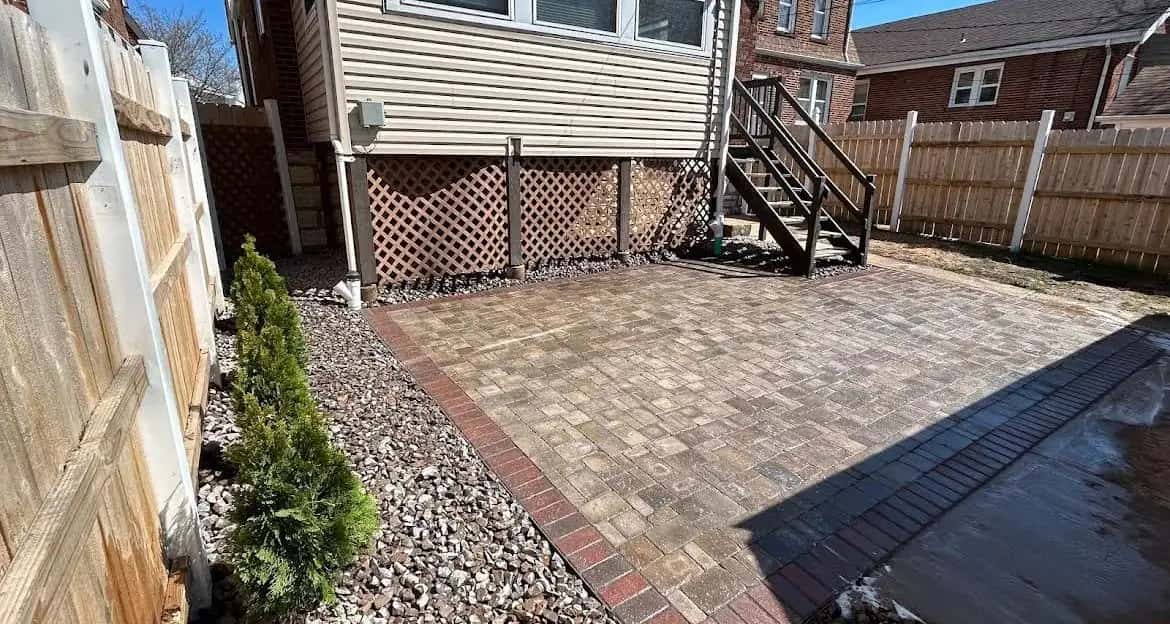 Paver patio with brick border and river rock beside a house