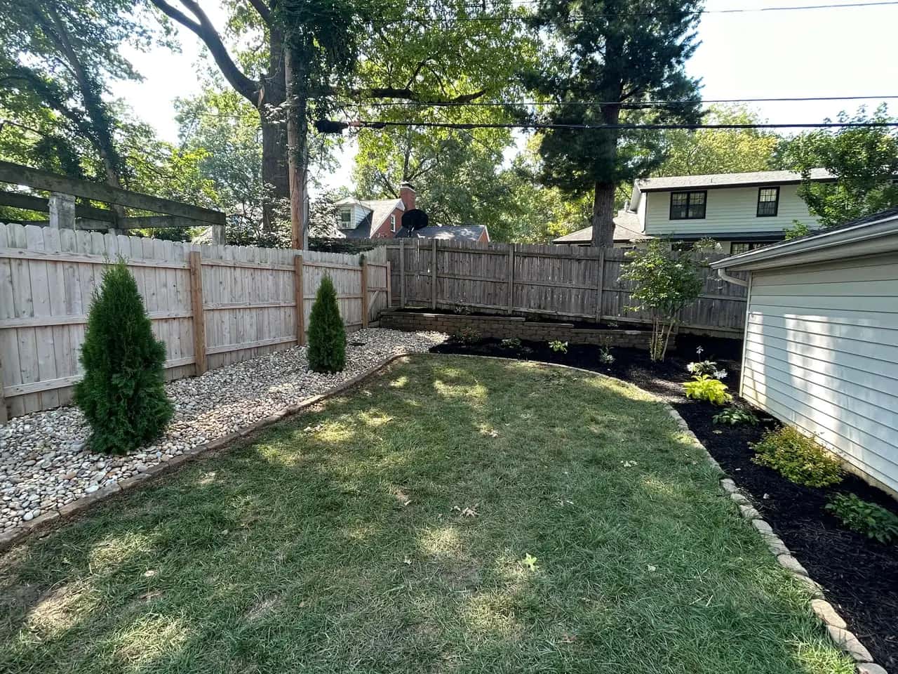 Backyard with privacy trees, mulch and river rock